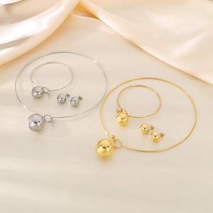 Detailed view of hollow sphere jewelry sets in gold and silver on beige silk fabric