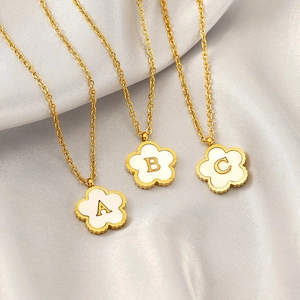 Close-up of golden titanium steel shell flower necklaces with alphabet pendants A B C