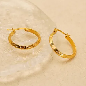 Gold-plated stainless steel hoop earrings with Greek key pattern on warm background