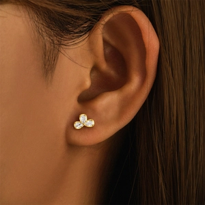 Detail of s925 silver golden clover stud earring with zircons on model ear