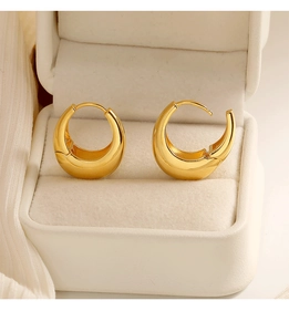 Macro detail of gold chunky C-hoop earrings featuring a high-polish mirror finish and clasp