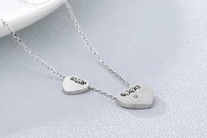 Makroaufnahme von Herzanhängern aus Silber mit LOVE Gravur an einer feinen Gliederkette