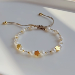 Baroque pearl bracelet with gold clover charms and adjustable hand-woven beige cord
