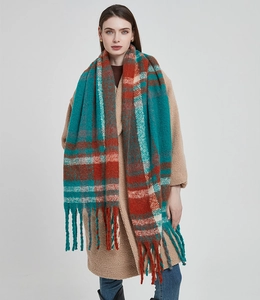 Detail of teal and brick red plaid scarf featuring thick tassels and soft yarn texture