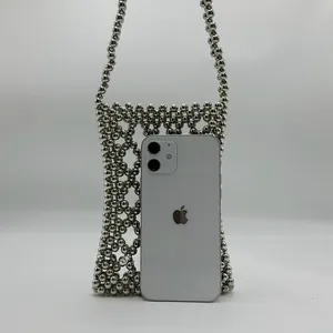Detail of silver metal bead lattice phone bag with pearls and a mobile phone for scale