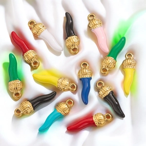 Colorful Italian Cornicello pendants in gold finish on white silk fabric background