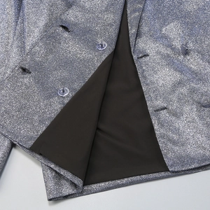 Close-up of silver sequin blazer featuring transparent buttons and black lining texture