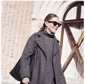 Dettaglio di un cappotto di lana grigio scuro a spina di pesce con occhiali da sole