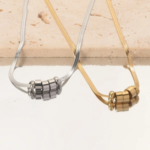 Detailed close-up of gold and silver snake chain necklaces with bead pendants on a mirror