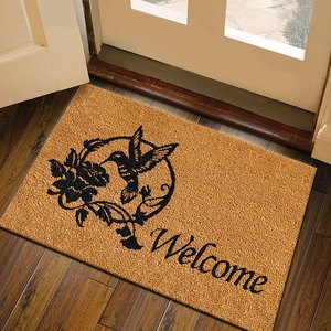 Brown welcome door mat with hummingbird and floral pattern on natural wood floor