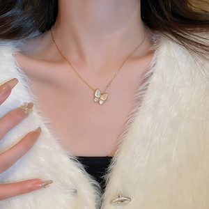Dettaglio di una collana a farfalla placcata oro con intarsio in madreperla su modella