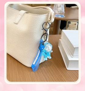 Detail of blue astronaut liquid keychain on leather bag with Dreamon strap and planet charm