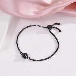 Dettaglio del bracciale regolabile nero con perla di proiezione su seta rosa
