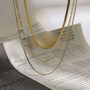 Detailed view of layered gold titanium steel necklaces with snake and box chain texture