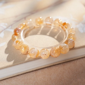 Détail macro d'un bracelet en perles de cristal jaune sur fond de lin texturé