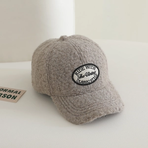 Close-up of fluffy sherpa fabric and vintage oval embroidery on the beige baseball cap