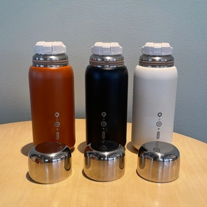 Three 316 stainless steel vacuum flasks in orange black and white on a wooden table