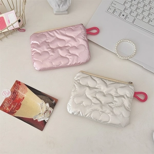 Detailed close-up of quilted heart-patterned coin purses in pink and silver fabric