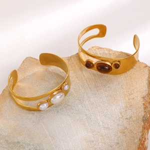 Detail of hollow oval pearl and tiger eye stone bangles on natural stone