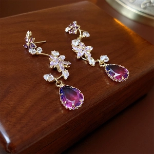 Close-up of golden flower earrings with purple gradient crystal waterdrop pendants