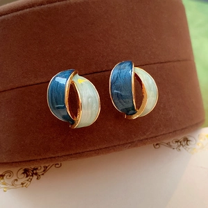 Macro shot of vintage gold-rimmed earrings with blue and white enamel on a jewelry box