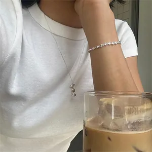 Detail of S925 silver candy necklace and heart chain bracelet worn for a chic daily look