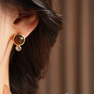 Nahaufnahme des Vintage-Harzohrrings in Gold mit tiefbraunem Ovalstein und funkelndem Strassstein