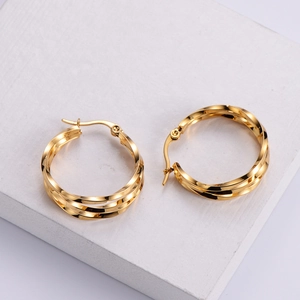 Close-up of golden twisted hoop earrings with a textured triple-layer woven design