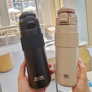 Close-up of black and beige vacuum insulated sport bottles with dual-use lids and handle