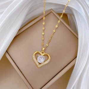 Macro detail of gold heart necklace with central cubic zirconia on silk background