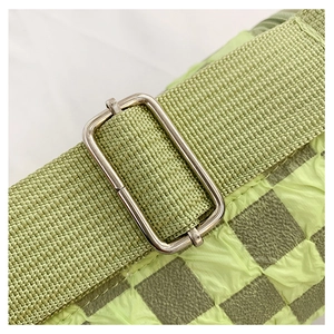 Detail of green checkerboard textured fabric and metal buckle adjustment on shoulder strap