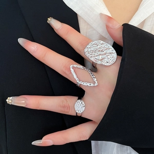 Detail of silver textured ring set showing oval and diamond shapes on hand