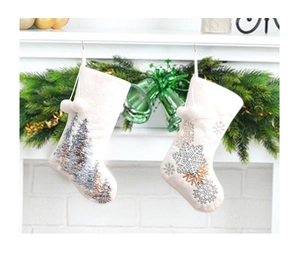 Close-up of white plush Christmas stockings with tree and snowflake embroidery on a fireplace