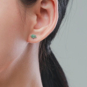 S925 sterling silver tree earrings with green zircon gems worn on a woman ear