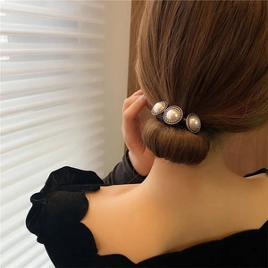 Elegante goma retro para el pelo con tres perlas doradas para un peinado de moño bajo