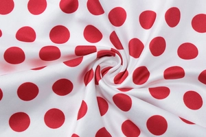 Détail du tissu blanc à pois rouges montrant une texture satinée lisse et brillante