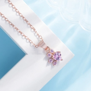 Macro shot of rose gold cat paw pendant with purple heart stone and water ripple background