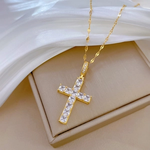 Macro shot of a luxury gold-plated cross pendant with cubic zirconia on a silk background