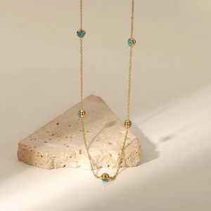 Detail of 18K gold plated chain with five blue turquoise evil eye beads on stone