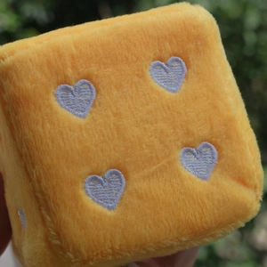 Macro shot of yellow plush car dice with soft purple heart embroidery detail