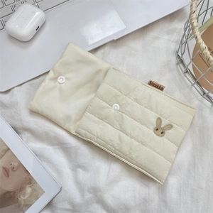 Detailed close-up of quilted cotton storage bag with cute rabbit embroidery and brand tag