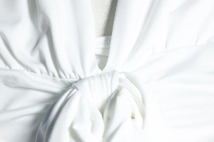 Macro detail of white halter dress featuring a front knot design and knit texture