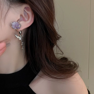 Close-up of model wearing silver long tassel earrings with purple stones and rose details