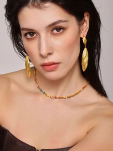 Detailed view of 18k gold plated striped shell drop earrings and colorful necklace