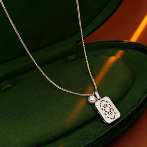 Detailed view of silver zircon pendant necklace in a luxury green velvet jewelry box