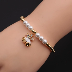 Détail d'un bracelet de Noël avec perles dorées et pendentifs cloches en zircon au poignet