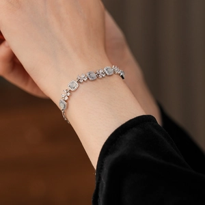 Détail d'un bracelet fleuri argenté avec pierres bleu clair et zircons porté au poignet