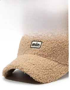 Close-up of khaki teddy fleece baseball cap featuring embroidered min letter patch