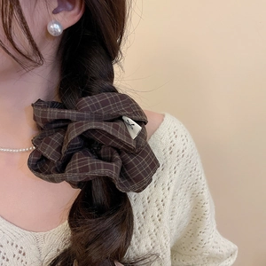 Deep brown plaid fabric scrunchie styled on a braided ponytail with soft lighting