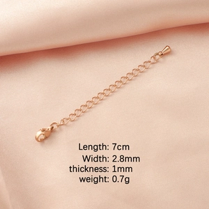 Macro detail of rose gold extender chain with lobster clasp on pink silk background